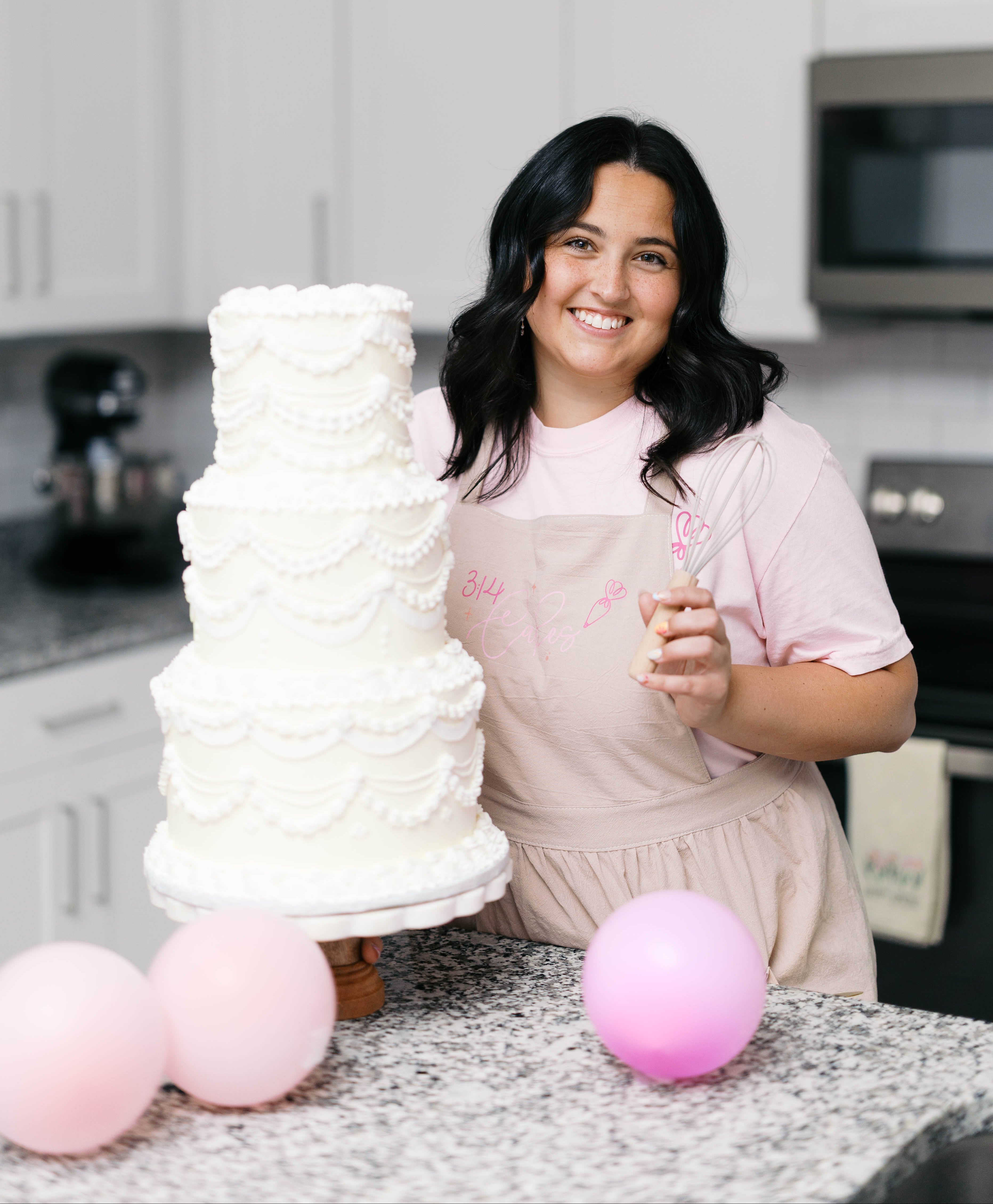 Woman in a kitchen with a decorated cake and balloons