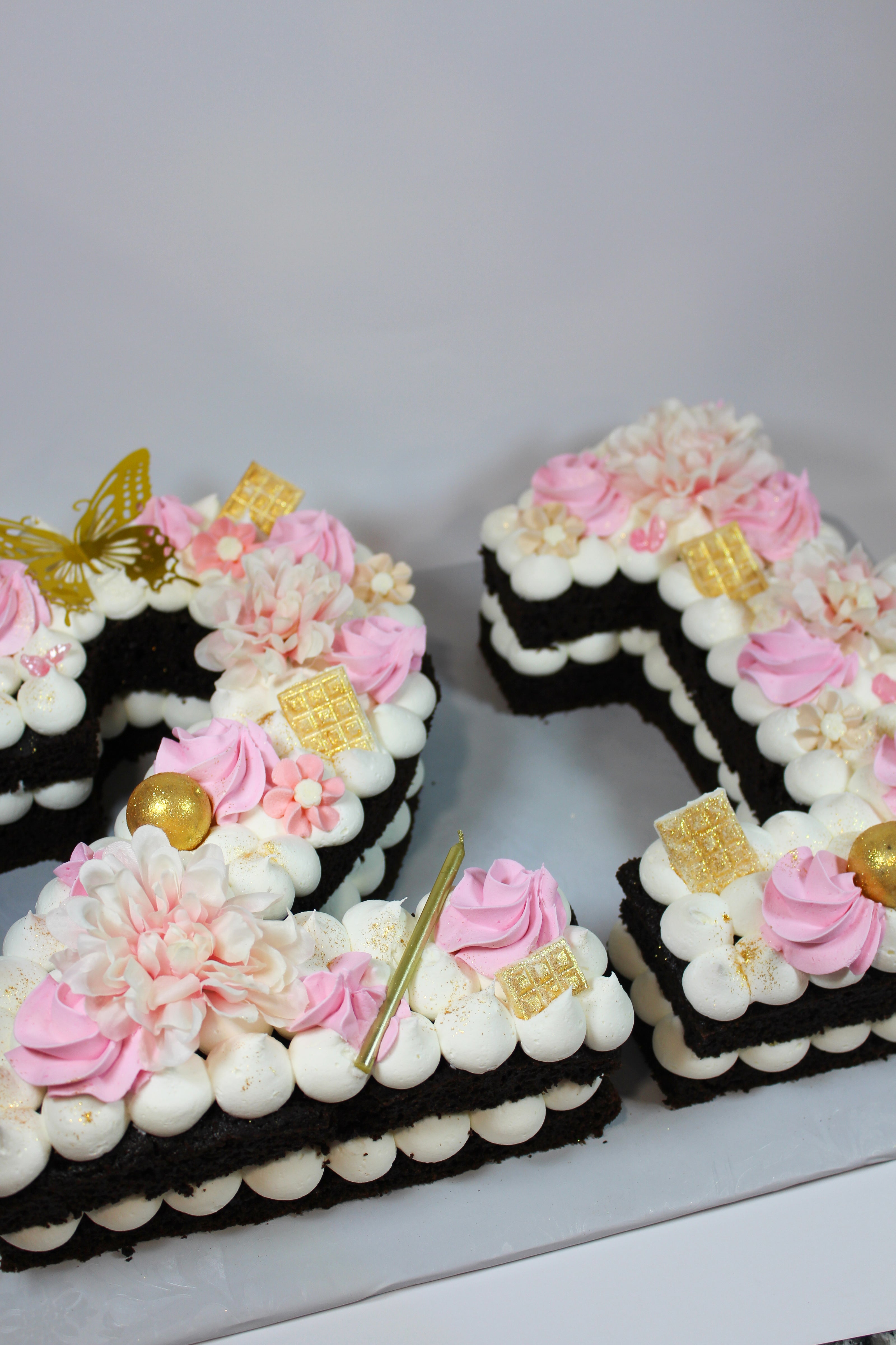 Decorative number '1' cake with flowers and gold accents on a white background