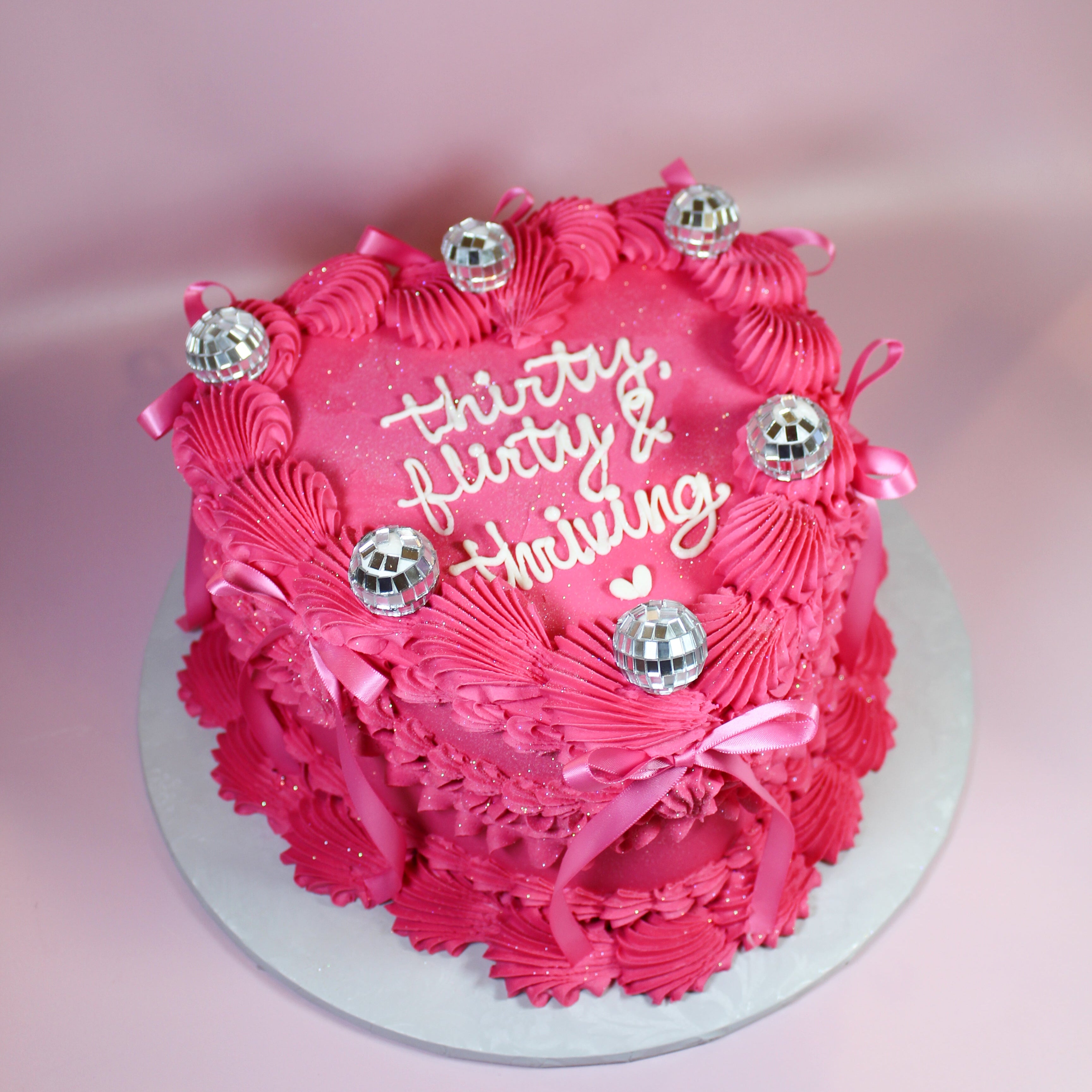 Pink birthday cake with decorative elements on a pink background