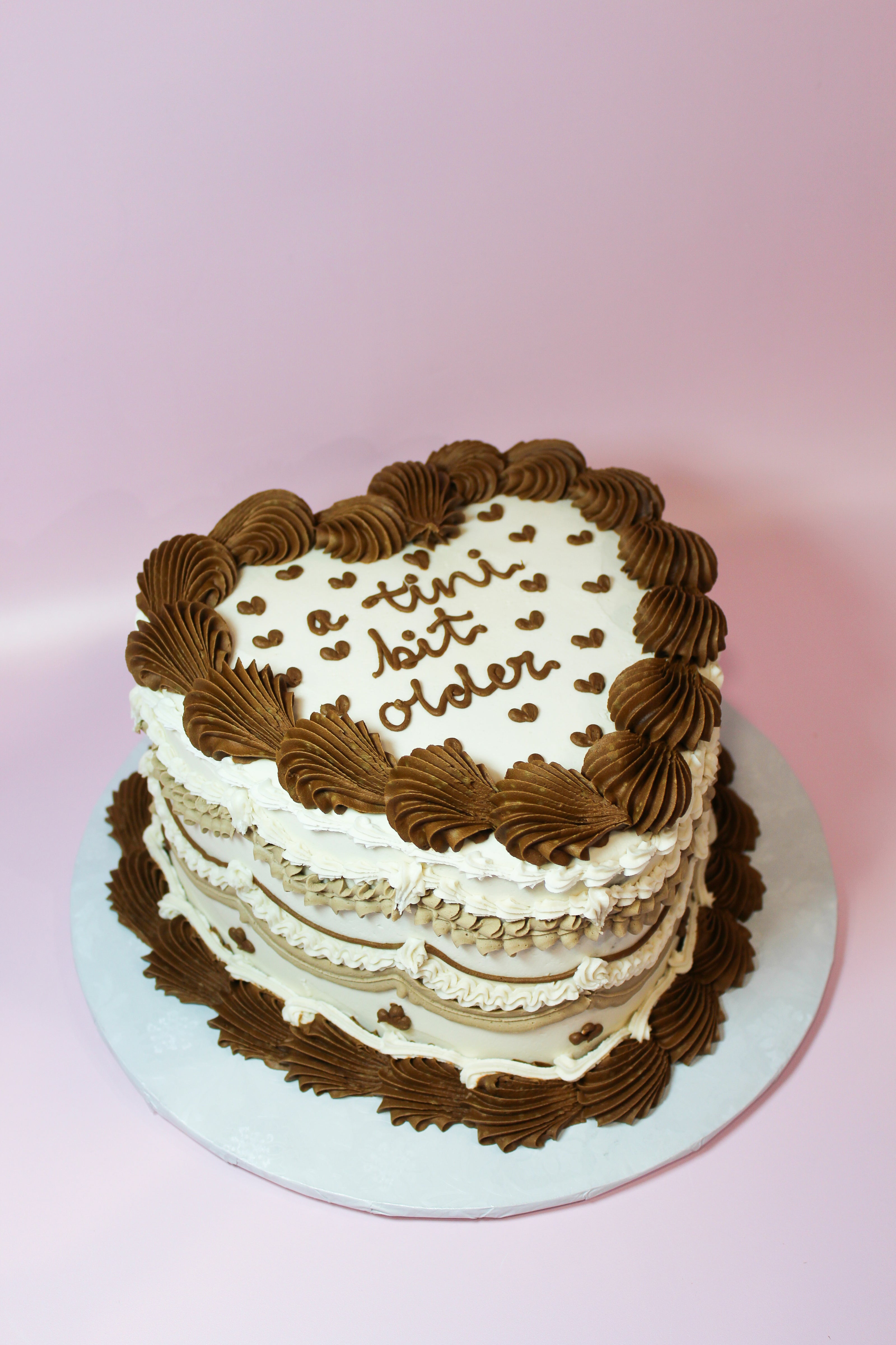 Two-layer cake with chocolate and white frosting on a pink background