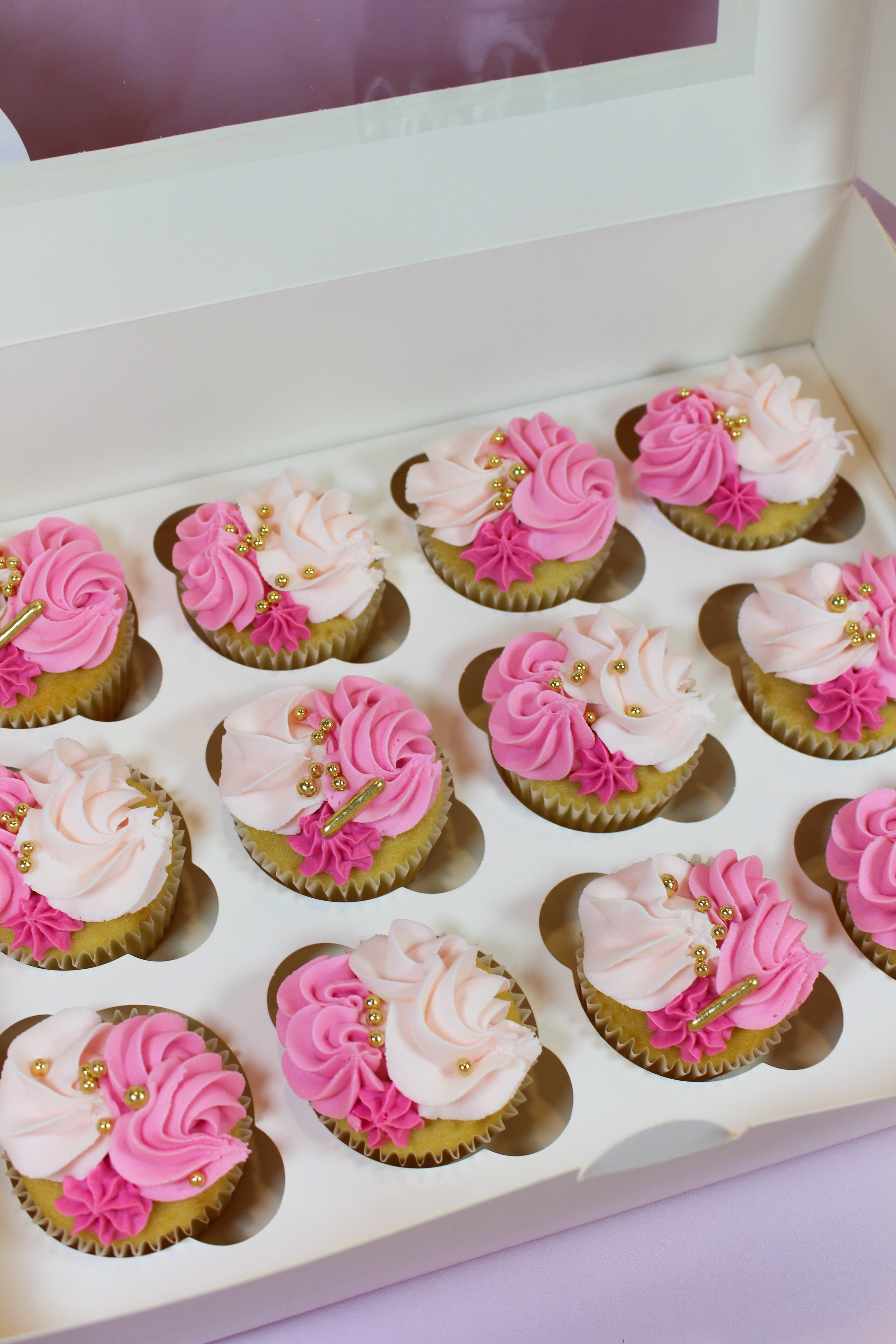 Box of cupcakes with pink and white frosting