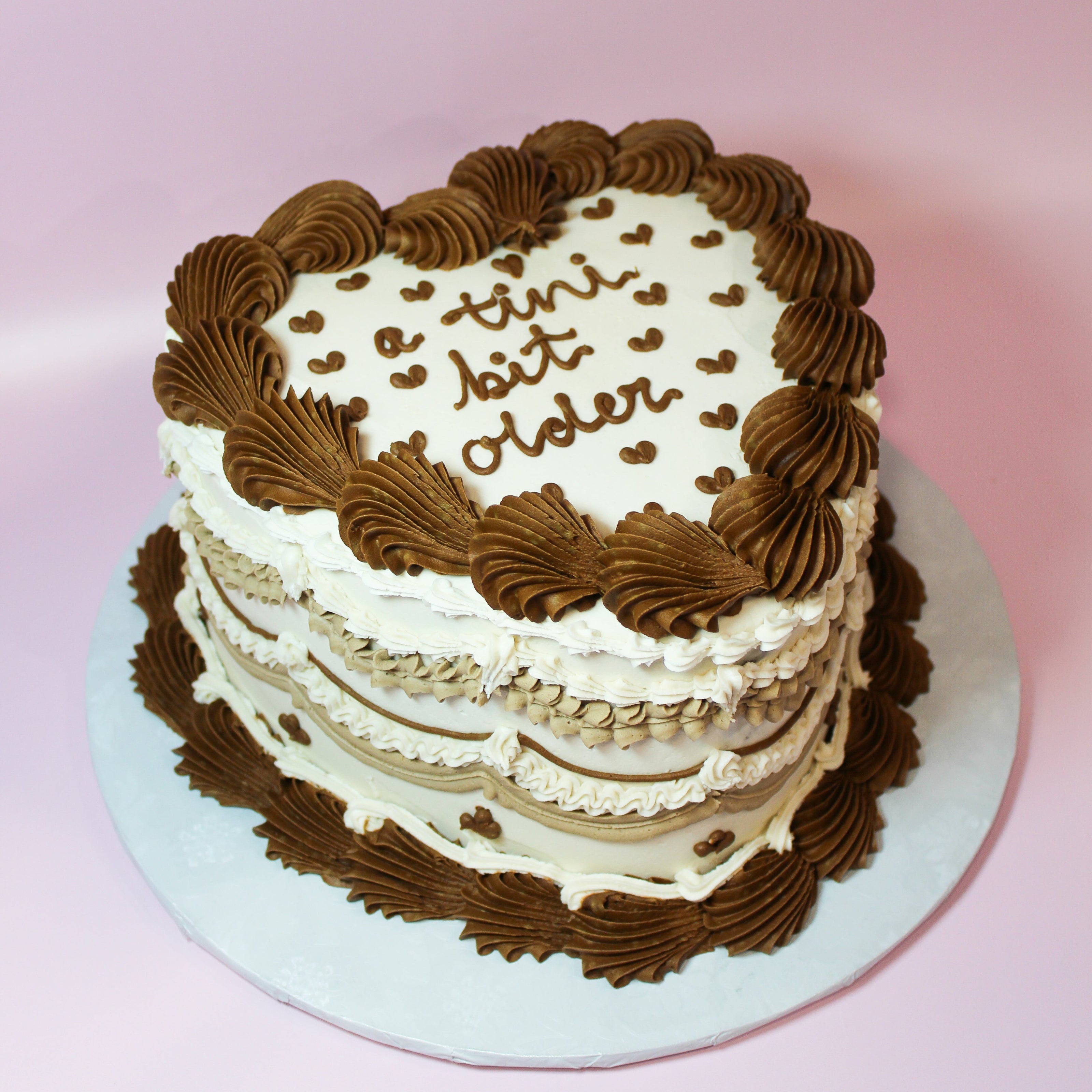 Two-layer cake with chocolate and white frosting on a pink background