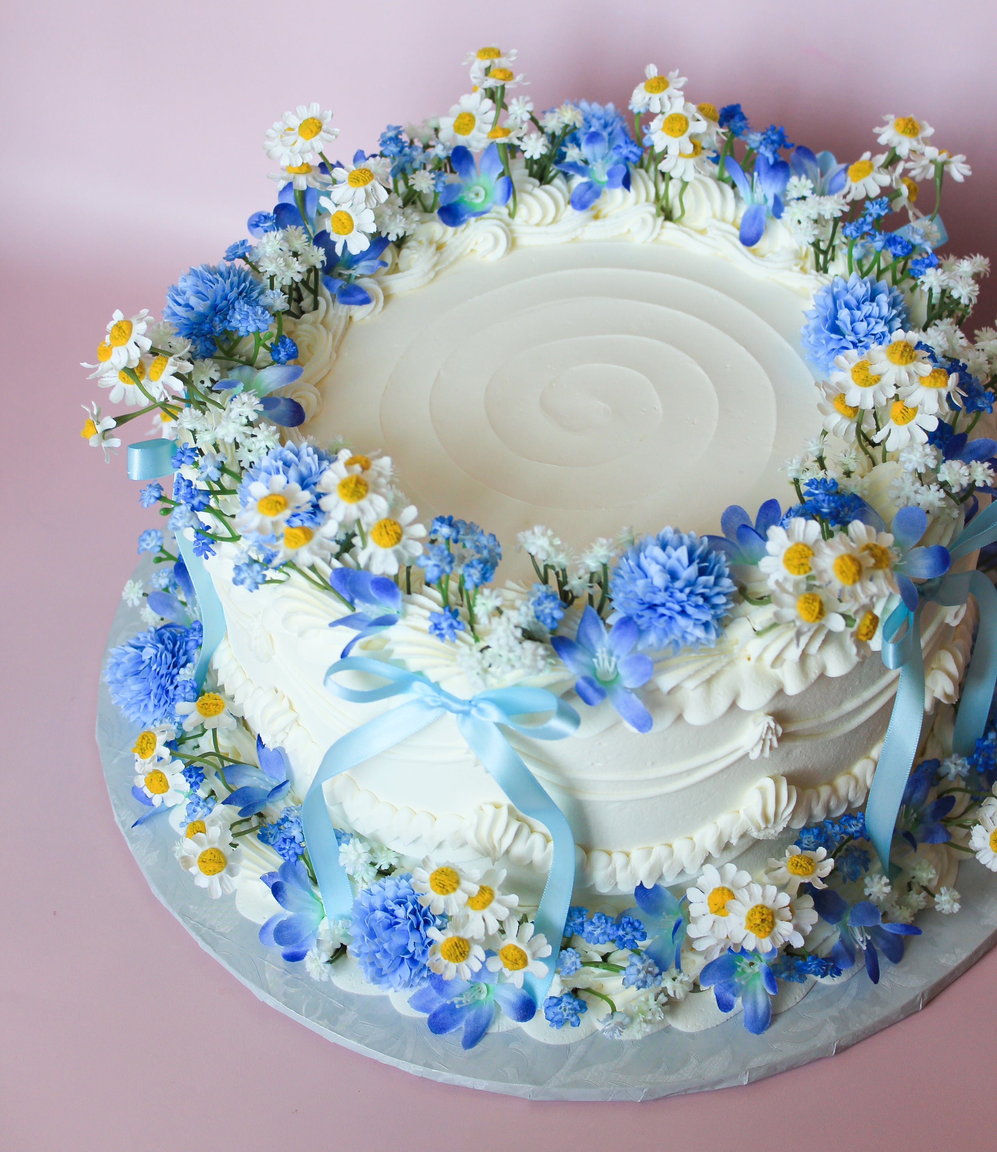 Decorative cake with blue and white flowers on a pink background