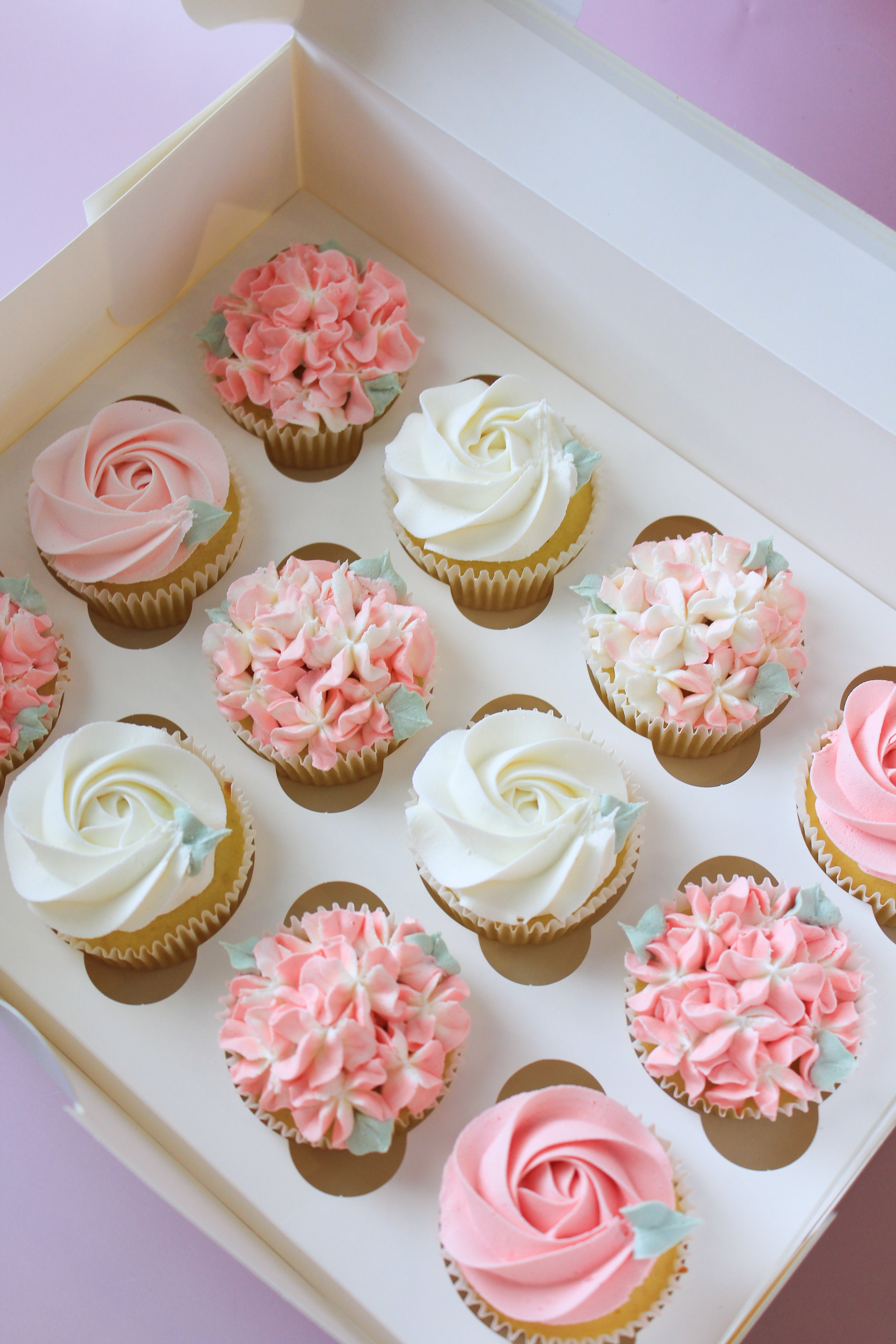 Decorative cupcakes in a box with pink and white frosting