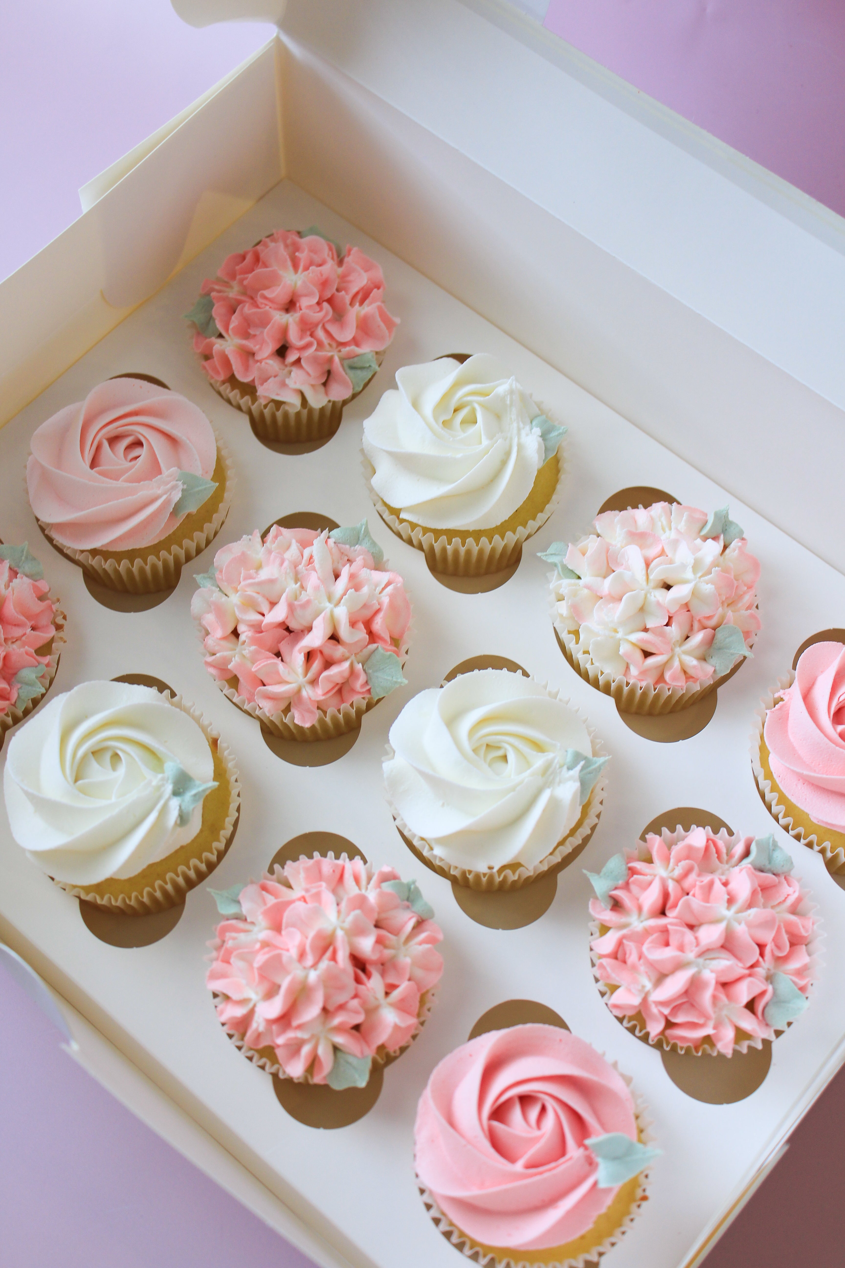 Decorative cupcakes in a box with pink and white frosting