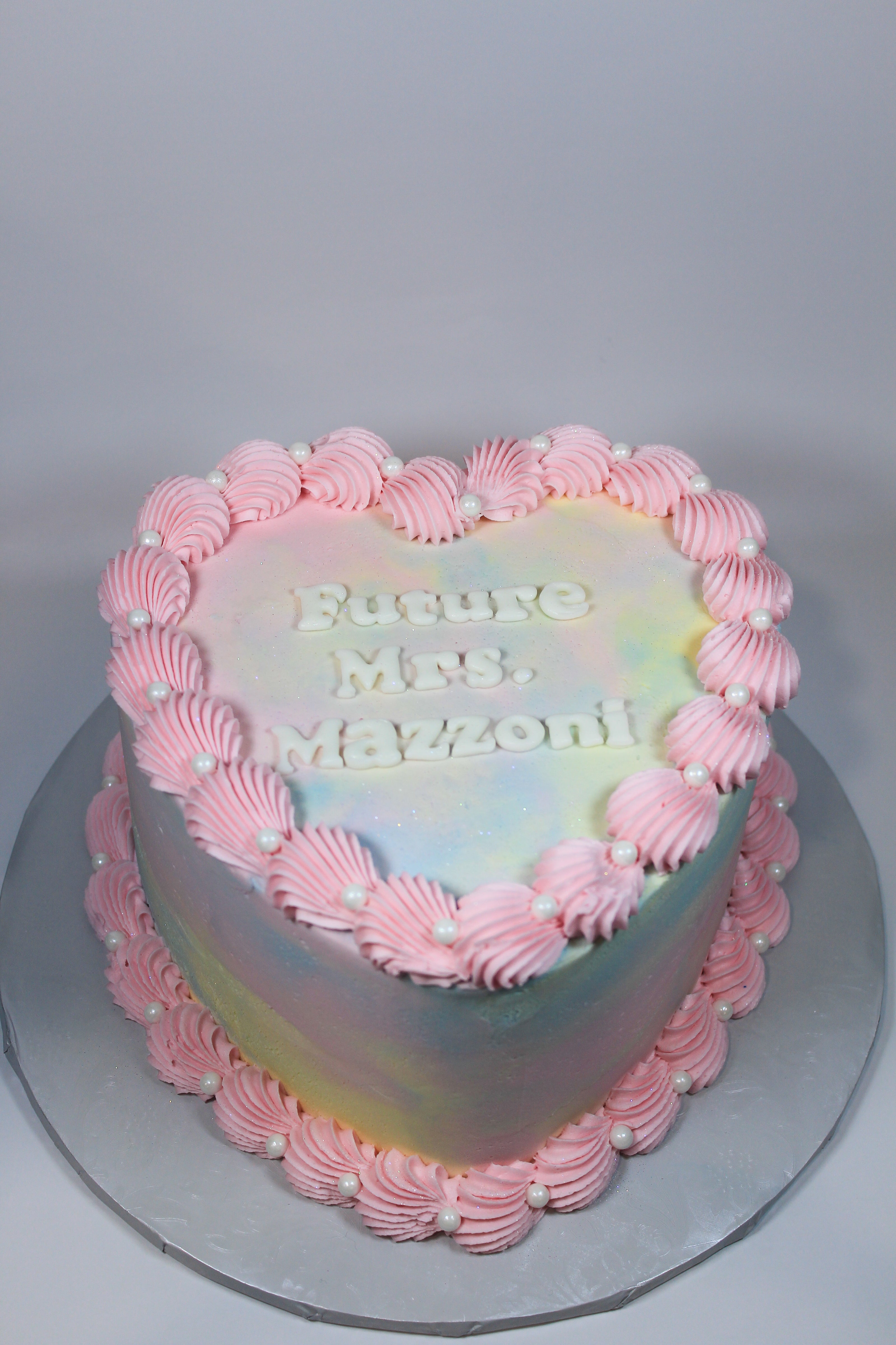 Heart-shaped cake with pink frosting and text on a gray background