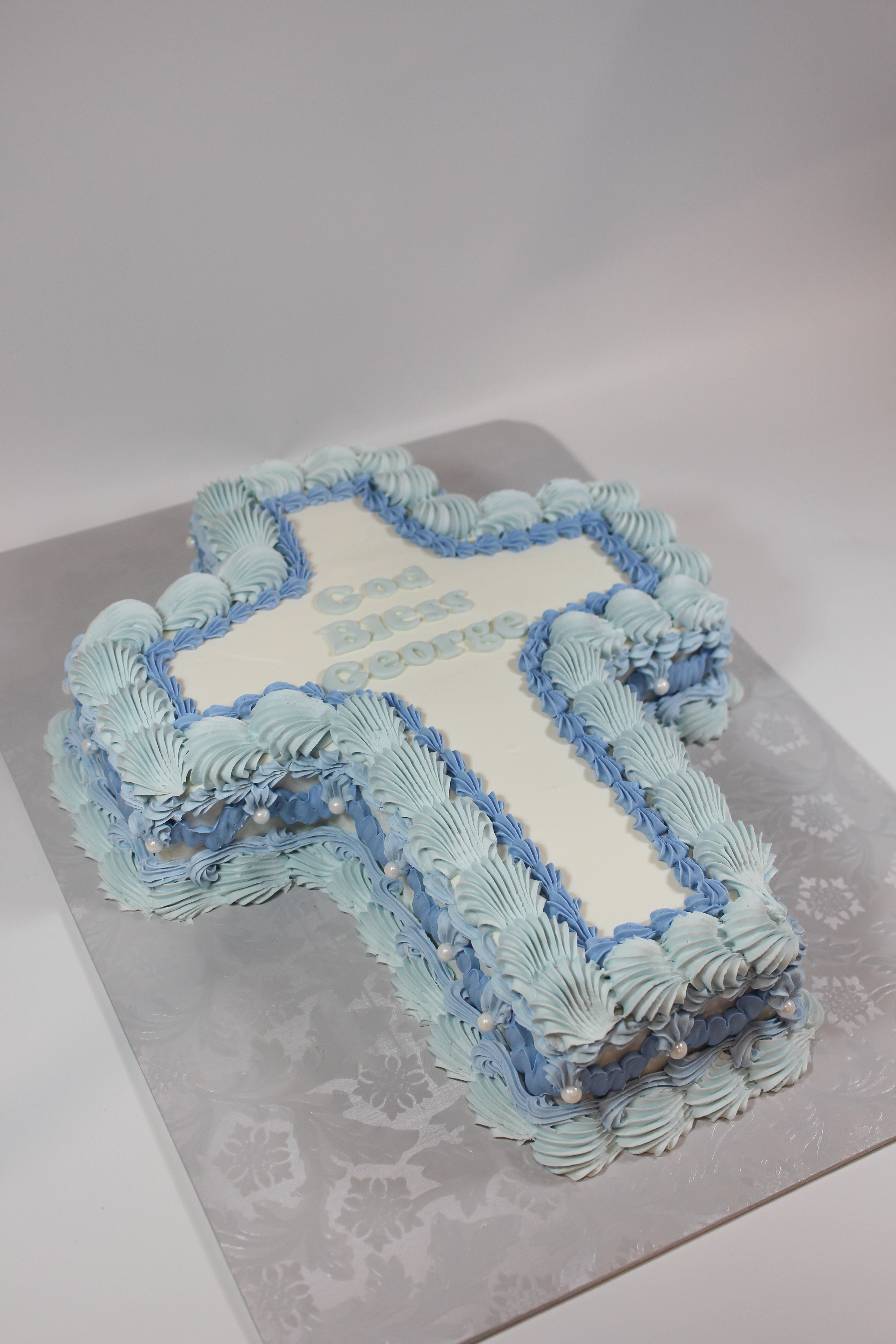 cross cake with blue and white frosting on a gray surface